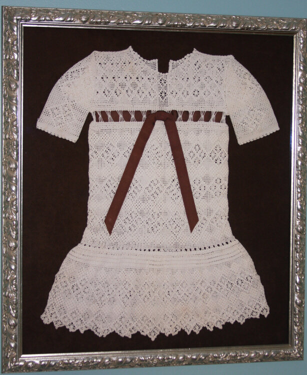Shadowbox of an old crocheted baby dress